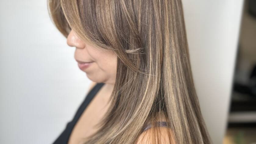 A woman with ash brown hair and subtle blonde highlights flowing elegantly.