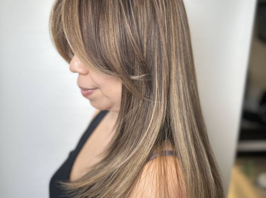 A woman with ash brown hair and subtle blonde highlights flowing elegantly.